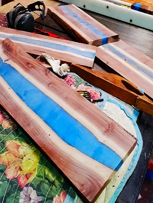 A beautiful live-edge Black Walnut charcuterie board with a vibrant blue epoxy river.