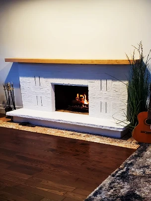 A renovated fireplace with a new plaster finish and a custom solid wood mantel.