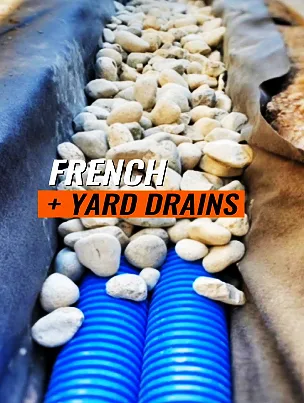 An excavated trench for a French drain system showing layers of pipe and gravel.